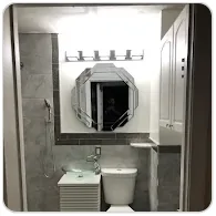 Finished bathroom with gray wall tile and an octagonal mirror
