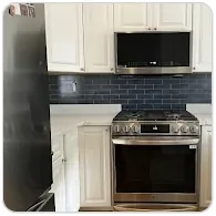 Navy subway tile kitchen backsplash behind a stainless steel range